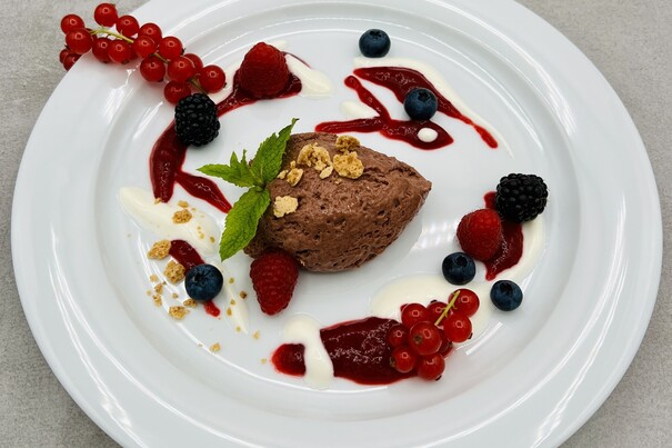 Mousse Schoko-Trüffel mit Himbeer-Fruchtpüree, Honig-Sauerrahm, Waldfrucht Dekor und Amarettinibröseln